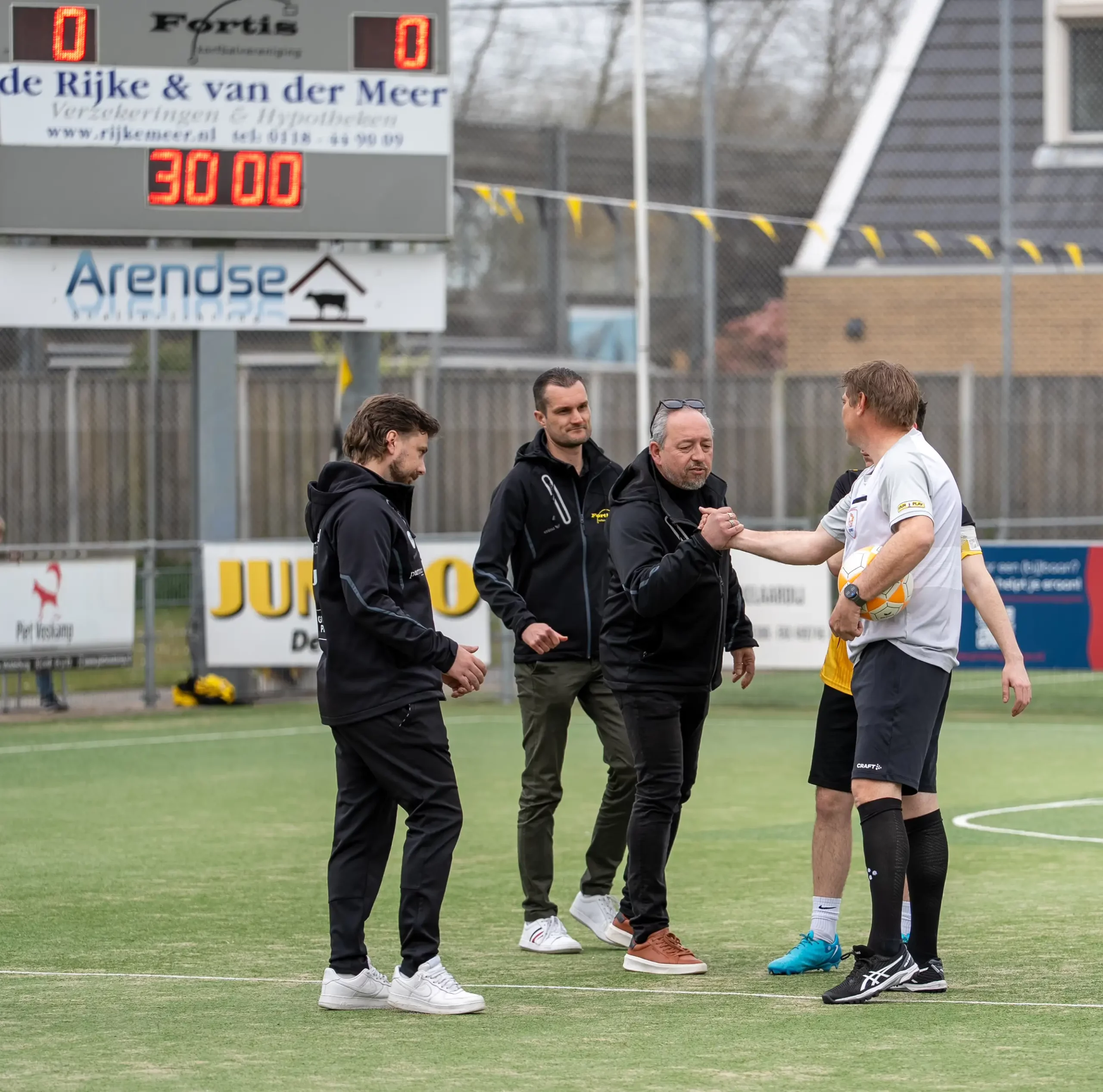 Fortis-speler en begeleiders op het korfbalveld