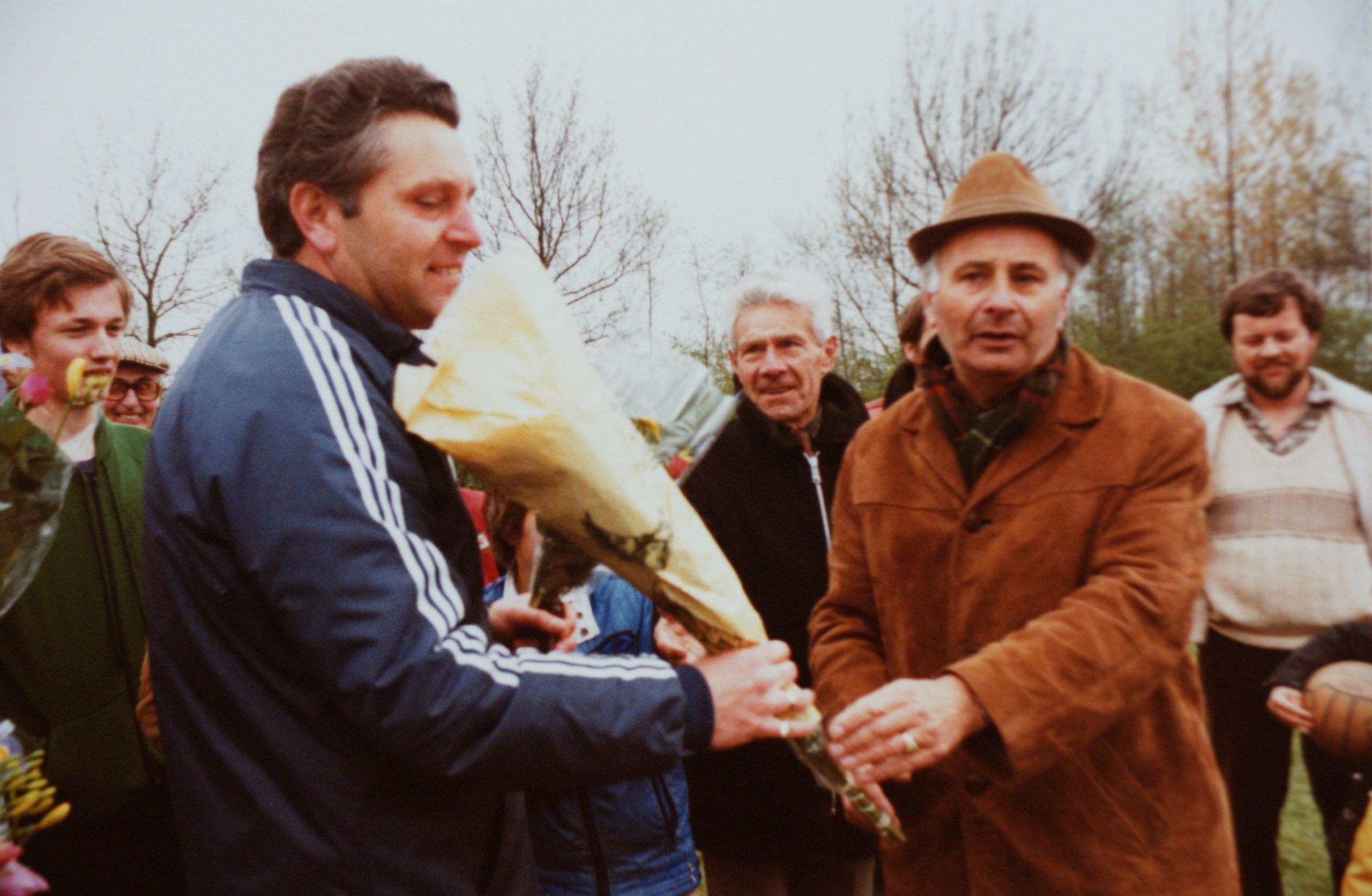 Bij een bijeenkomst op het veld worden bloemen overhandigd.