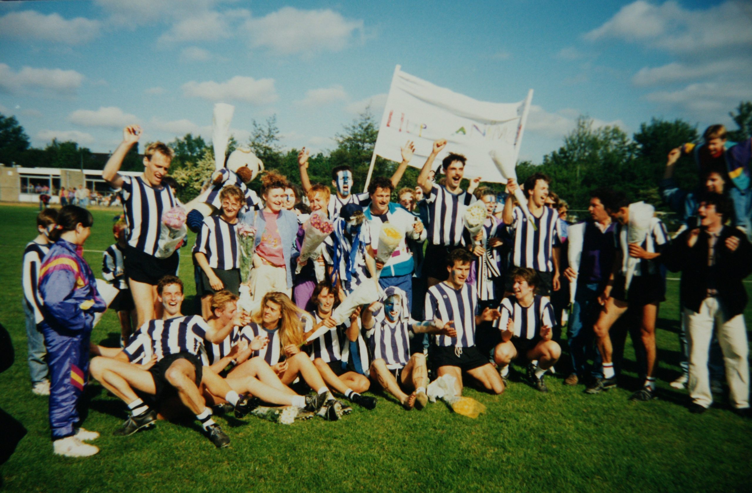 Spelers en supporters vieren samen feest op het veld.
